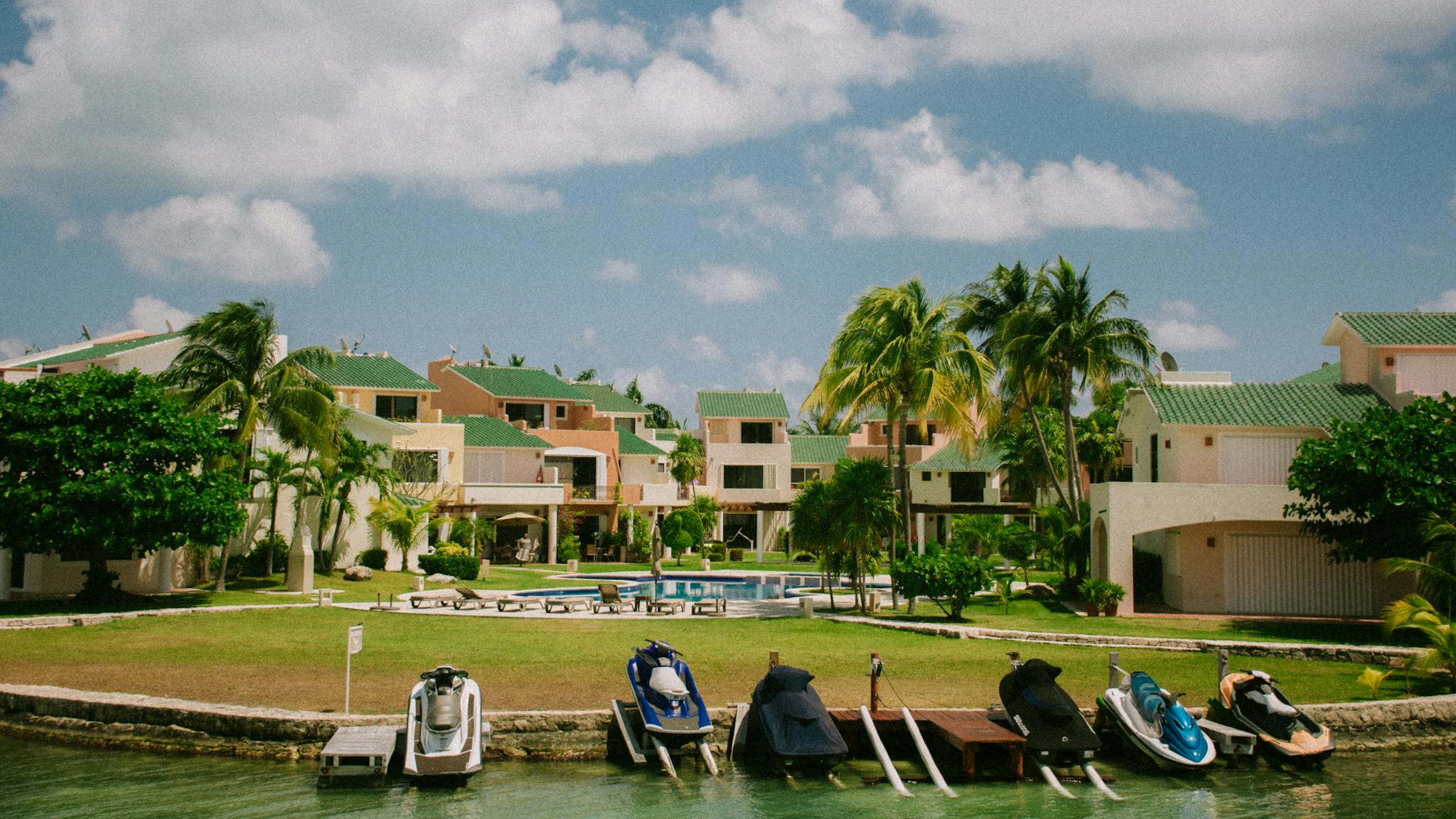 Serene tropical resort featuring lush palm trees, vibrant greenery, and jet skis on a sunlit day.
