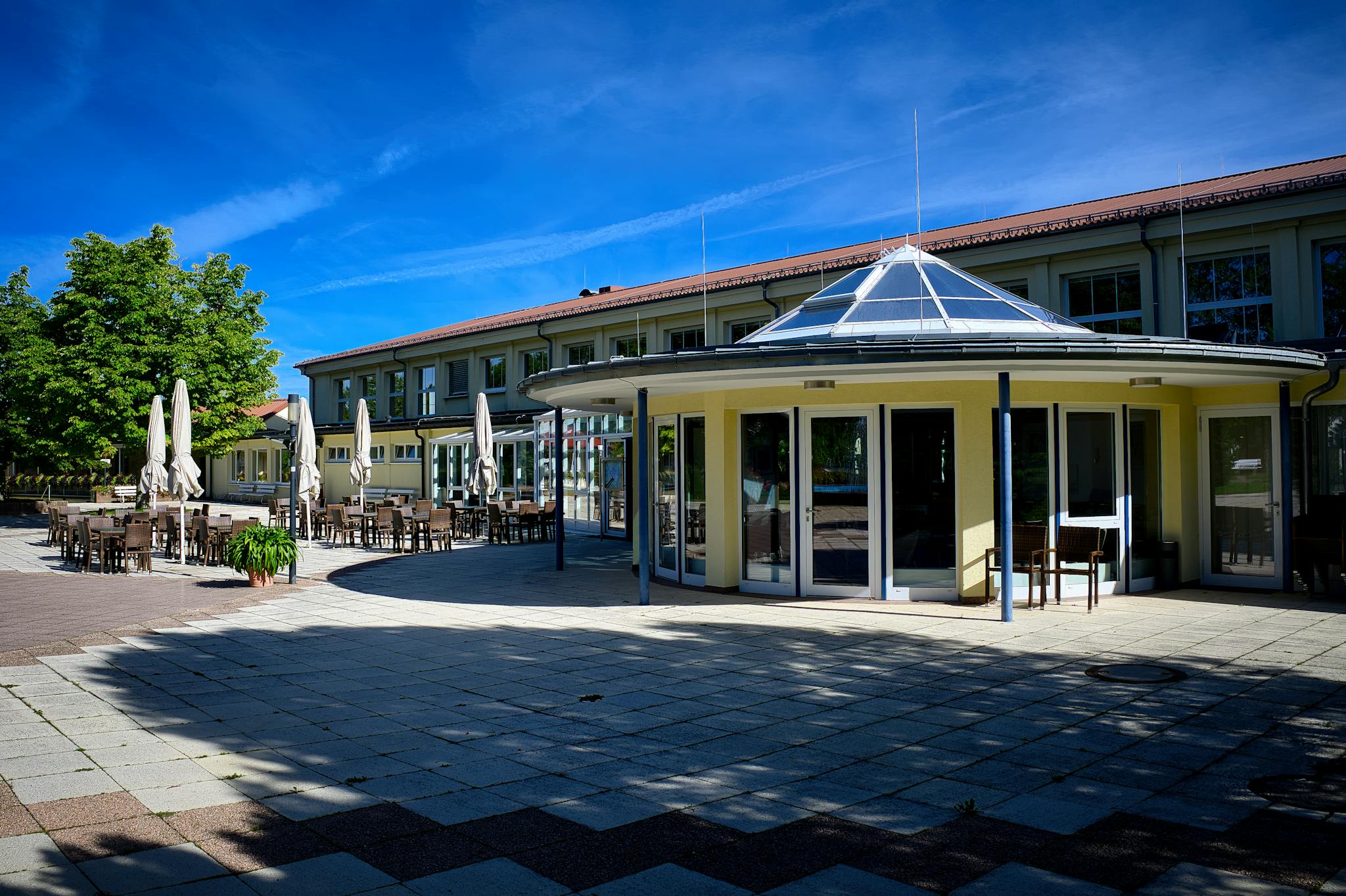 Spacious patio area of a modern hotel in Schömberg, Germany, under clear blue skies.