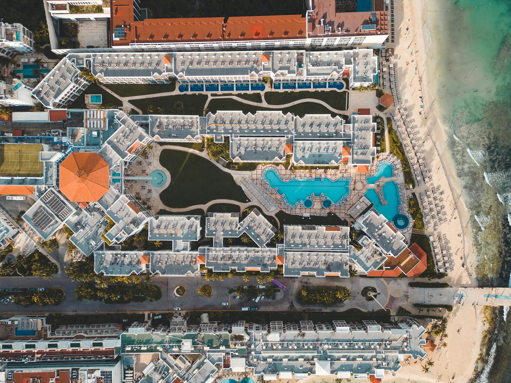 Stunning aerial view of a luxury resort in Playa del Carmen, featuring pools and beach access.
